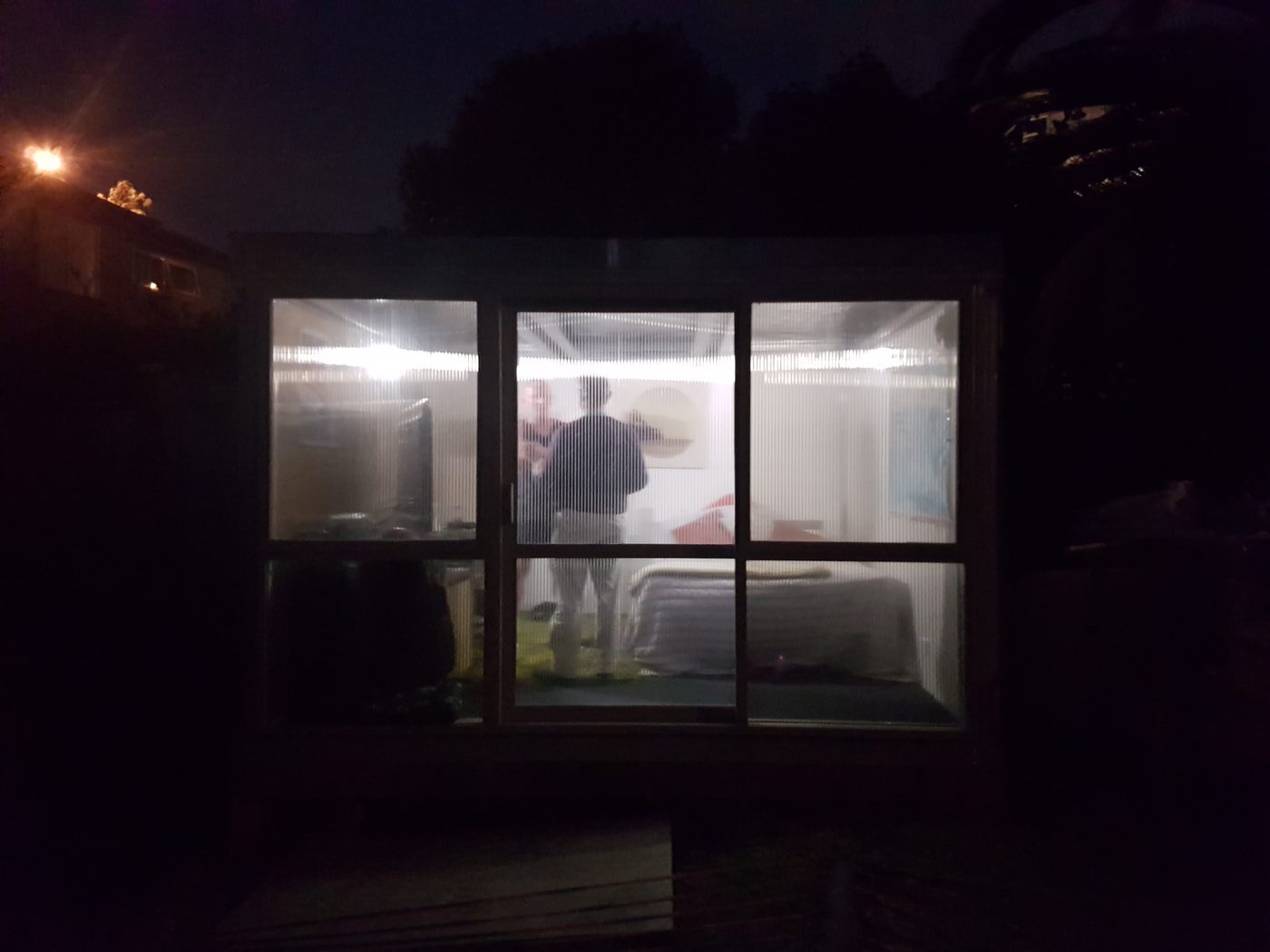 2018 proof-of-concept module at night, occupied — exterior glow from interior lighting, silhouettes visible inside